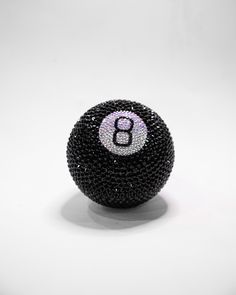 a black beaded ball with the number eight on it's side, sitting in front of a white background