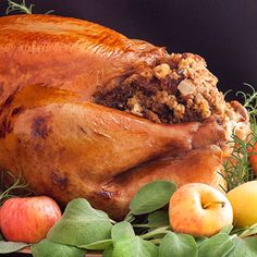 a whole turkey sitting on top of a table next to apples and other fruit pieces