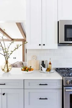 a kitchen with white cabinets and stainless steel appliances, including a stove top oven and microwave