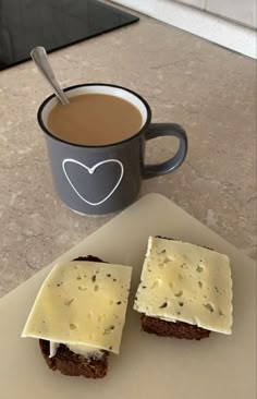 two pieces of bread with cheese on them next to a cup of coffee