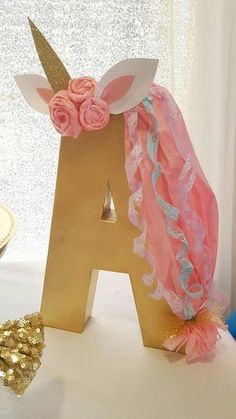 a gold letter with pink and blue flowers on it next to a cupcake holder