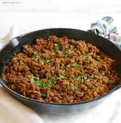 a pan filled with food sitting on top of a white table next to a cloth