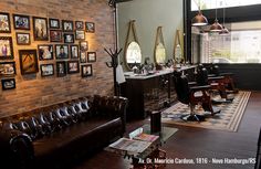 a living room filled with furniture next to a brick wall covered in framed pictures and photos