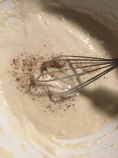 a whisk in a bowl with some brown stuff