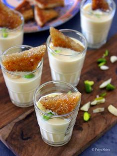 small glasses filled with food sitting on top of a wooden cutting board