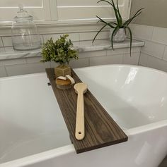 a wooden spoon and brush sit on a bathtub tray next to a potted plant