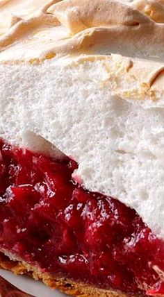 a close up of a piece of cake on a plate with strawberry jam and whipped cream