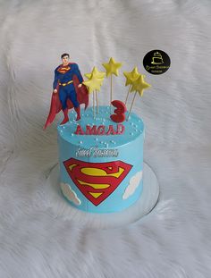 a birthday cake with a superman theme and stars on the top is decorated in blue frosting