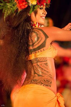 a woman with flowers on her head and body is dancing in an orange skirt while wearing a flower crown