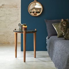 a cat sitting on top of a bed next to a table with a candle in it