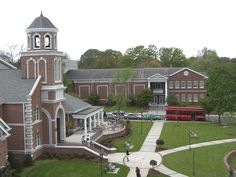 an aerial view of a campus with a red bus parked on the grass and people walking around