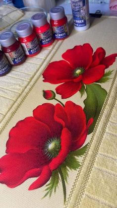 some red flowers are sitting on a table next to thread markers and glues,