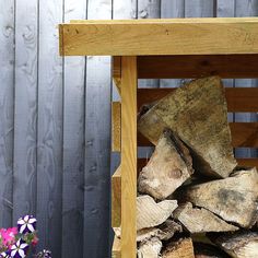 a pile of wood sitting on top of a wooden bench next to a flower pot