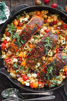 two fish fillets in a skillet with tomatoes, olives and other vegetables