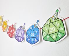 a string of colorful paper toys hanging on a white wall with numbers and figures attached to them