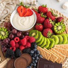 a platter filled with fruit, crackers and dip