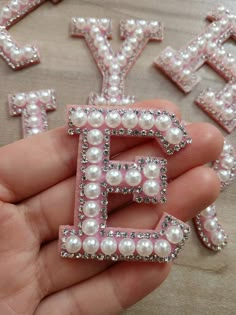 someone is holding some type of letter made out of pearls and other things in the shape of letters