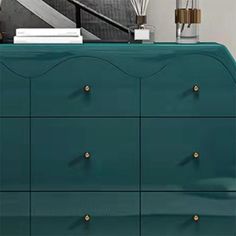 a green dresser with gold knobs and drawers