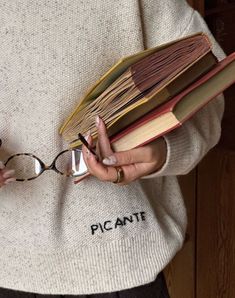 a woman holding a stack of books in her hands