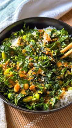 a pan filled with rice and vegetables on top of a table next to chopsticks