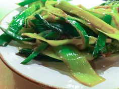 a white plate topped with green vegetables on top of a wooden table