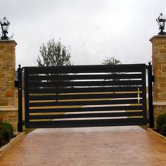 an iron and wood gate in front of stone pillars