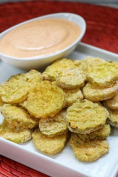 some fried food on a white plate with dipping sauce