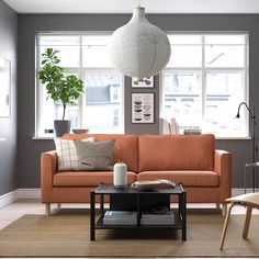 a living room with an orange couch and coffee table in front of the window,