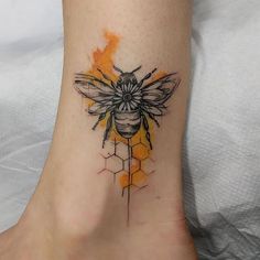 a tattoo on the foot of a woman with a bee and honeycombs design