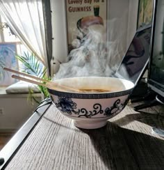 a bowl of soup with chopsticks in front of a laptop computer on a desk