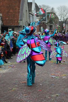 some people are walking down the street with kites in their hands and colorful costumes