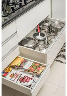 an open drawer in the middle of a kitchen with pots and pans on it