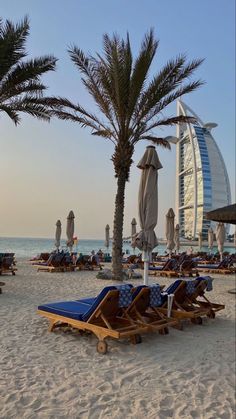 lounge chairs and umbrellas on the beach with burj al arab in the background