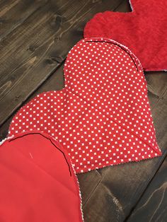 three red heart shaped pieces laying on top of a wooden floor