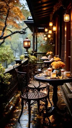 an outdoor table and chairs on a porch with lanterns hanging from the ceiling over it