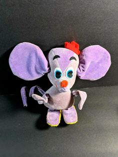 an elephant stuffed animal with a red bow on its head sitting next to a black background