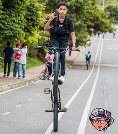 a man riding a bike down the middle of a street with people walking and biking behind him