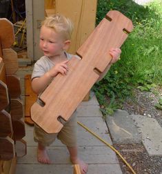 a young boy holding a wooden object in his hands