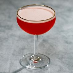 a close up of a drink in a wine glass on a table with a gray background