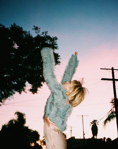 a woman is jumping in the air with her arms up and legs spread wide out