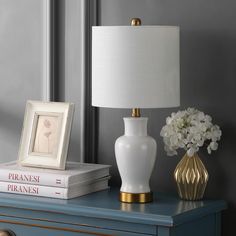 a white lamp sitting on top of a blue table next to a book and flowers