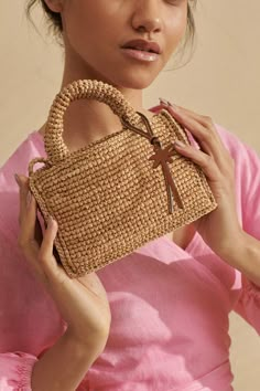 a woman is holding a straw bag in her hands