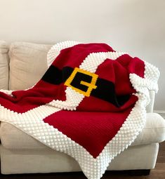 a blanket that is sitting on top of a couch next to a white sofa with a santa hat on it