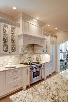 a kitchen with marble counter tops and white cabinets