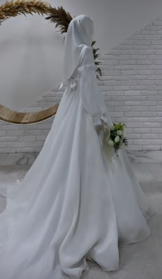 a woman in a white wedding dress standing next to a brick wall with a mirror behind her