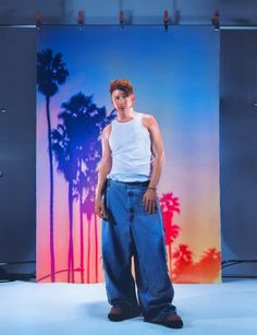 a man standing in front of a backdrop with palm trees