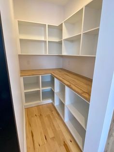 an empty room with white shelving and wood flooring on the side walk - in closet