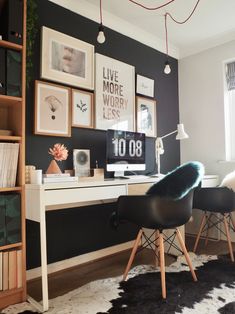 a home office with black walls and pictures on the wall, including a white desk