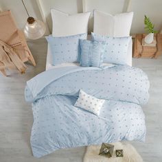 a bed with blue and white comforters on top of it next to a rug