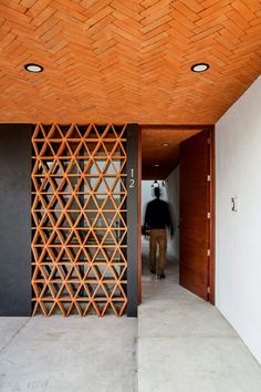 a man is walking into a room with wood paneling on the walls and ceiling